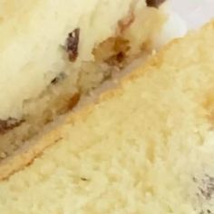 a close up of a piece of cake with white frosting and raisins