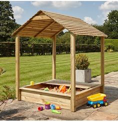 an outdoor play area with toys in the sandbox and a wooden gazebo over it