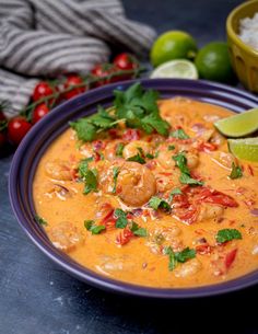 a purple bowl filled with shrimp and rice next to limes, cilantro, and tomatoes