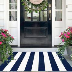 the front door is decorated with pink flowers and wreaths, along with two potted plants