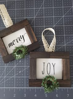 two small wooden frames with christmas signs on them, one is holding a wreath and the other has a sign that says merry