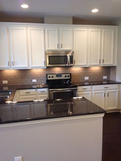 a kitchen with white cabinets and black counter tops