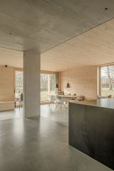 an open living room and dining area in a house with concrete floors, large windows, and wooden walls