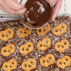 someone is dipping chocolate into pretzels on top of the cookie sheet and then drizzling them with melted chocolate