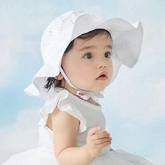 a baby wearing a white dress and bonnet