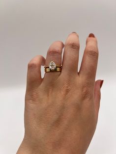 a woman's hand with a diamond ring on her left hand, against a white background