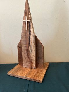 a small wooden church with a cross on the front and side, sitting on a table