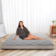 a woman sitting on top of a mattress in a room