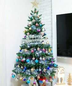 a decorated christmas tree in front of a flat screen tv