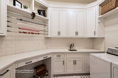 a laundry room with white cabinets and tile flooring