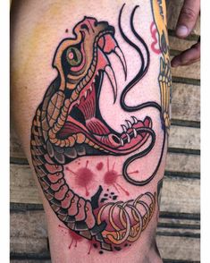 a tattoo on the leg of a man with a snake in it's mouth