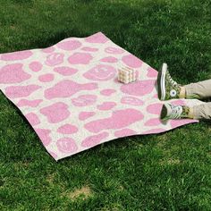 a person laying on top of a pink and white blanket in the grass with their feet up