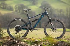 a blue mountain bike parked on top of a grass covered field