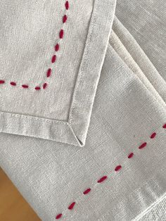 two pieces of white linen with red stitching on them