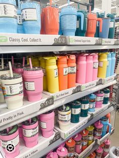 there are many different colors of cups on the shelves in this store and one is pink