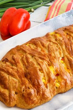 a close up of a pastry on a plate with tomatoes and peppers in the background