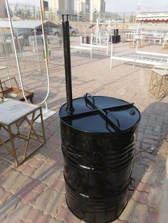 a large black barrel sitting on top of a brick floor