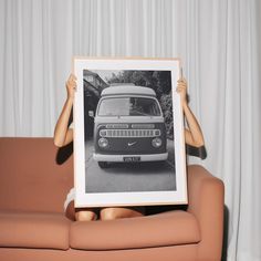 a woman holding up a black and white photo with an old truck in the background