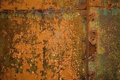 an old rusted metal surface with green and yellow paint peeling off the side,