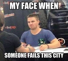 a man sitting at a table in front of a sign that says, my face when someone falls this city