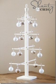 a white christmas tree with ornaments hanging from it's sides on a wooden table