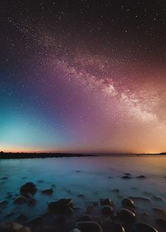 the night sky is filled with stars and bright purple hues as it reflects in the water