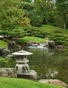 a lantern sitting on top of a rock next to a pond