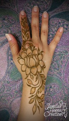 a woman's hand with hennap and flowers painted on the top of it