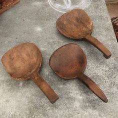 three wooden spoons sitting on top of a cement floor next to a pile of wood