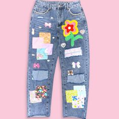 a pair of blue jeans with patches and flowers on them, against a pink background