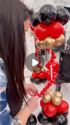 a woman is decorating red and black balloons