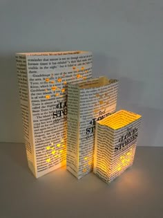 three lit up books sitting next to each other on top of a table in front of a white wall