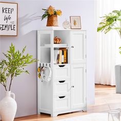 a white cabinet with drawers and shelves in the corner next to a potted plant