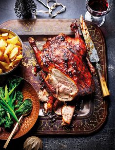 a roasting pan with meat, potatoes and broccoli next to it on a table