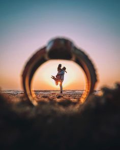 a person standing on top of a sandy beach under a magnifying glass with the sun setting in the background