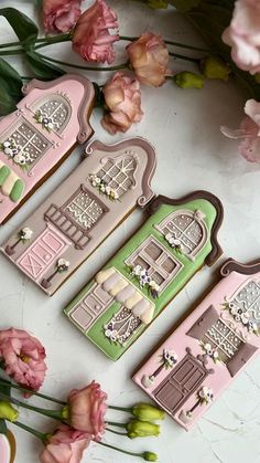 three decorated cookies sitting on top of a table next to some pink and green flowers