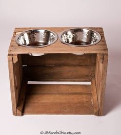 two stainless steel bowls are placed on a wooden stand