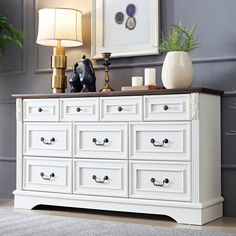 a white dresser with several drawers and two lamps