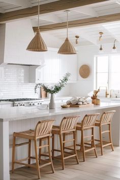 a kitchen island with four stools and three lights hanging from it's ceiling