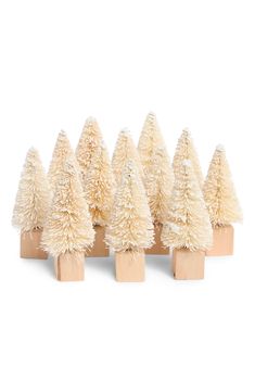 small white christmas trees are lined up on wooden blocks