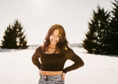 a woman standing in the snow with her hands on her hips