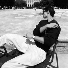 a man sitting on top of a bench next to a park