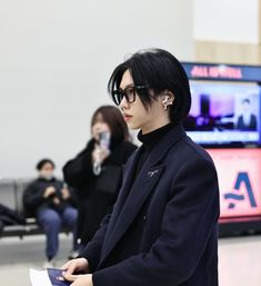 a man with black hair and glasses holding a piece of paper