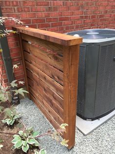 an air conditioner sitting on top of a wooden fence next to a brick wall