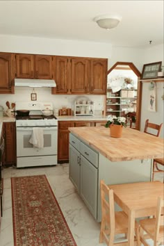 A kitchen with a green island and butcher block countertop. An oriental rug and and natural wood children's table. No Porch Backyard Ideas, Vintage Room Ideas, Moody French, Kitchen Minecraft, Ranch Cottage, Bloxburg Cottage, Elegant Cottage, Minimalist Cottagecore, Cozy Cottage Kitchen