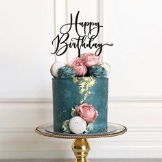 a blue cake with pink flowers and the words happy 90th on top is sitting on a gold pedestal