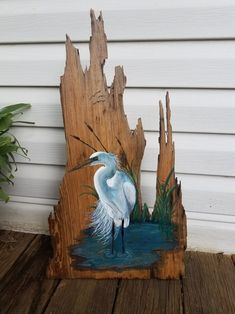 a white bird standing on top of a piece of wood