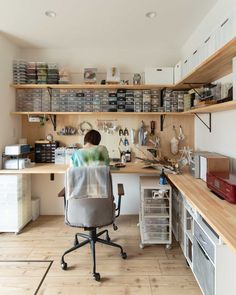 a person sitting at a desk in a room with lots of shelves on the wall