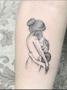 a woman's arm with a tattoo on it, holding a baby in her arms