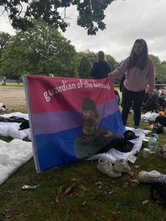 a woman standing next to a flag with a man's face on it in the grass